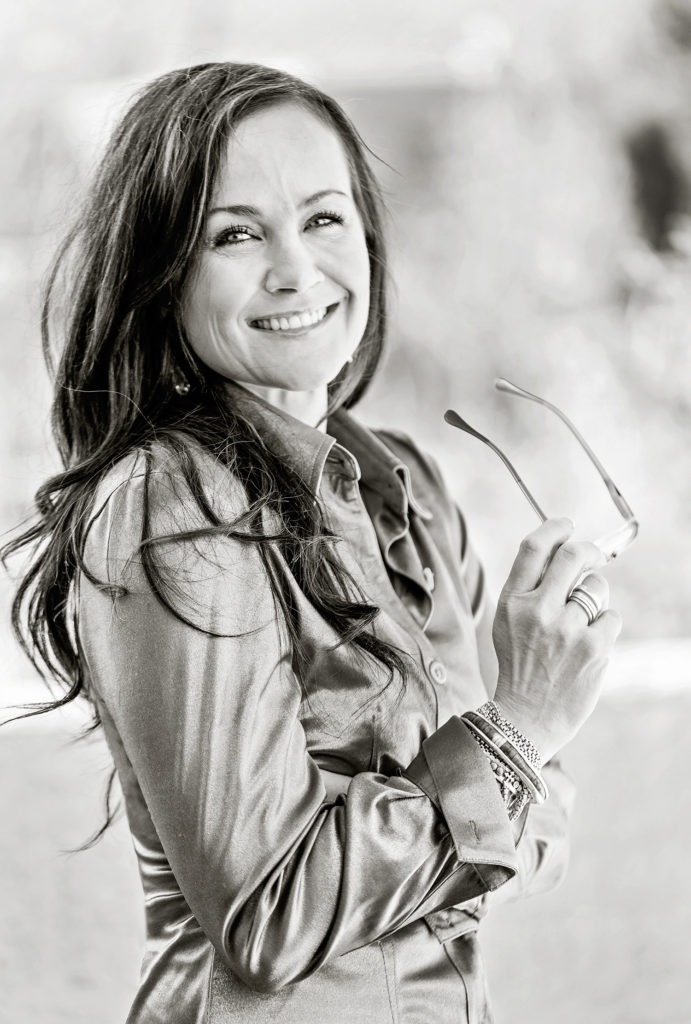 A woman holding glasses and smiling for the camera.